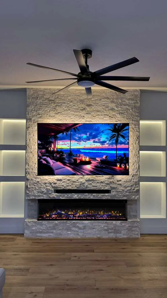 Stacked stone fireplace column with a backlit TV and a linear fireplace between lit niches
