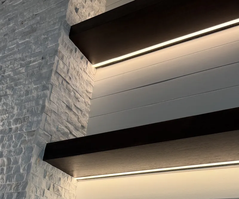 Espresso-tone floating shelves with an LED strip lighting the white shiplap below, beside the stone