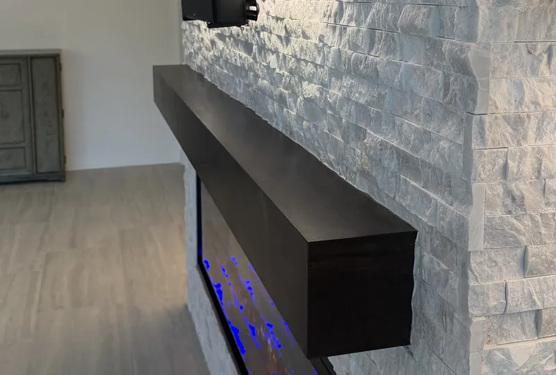 The espresso-tone mantel seen from the side, floating on the stacked stone