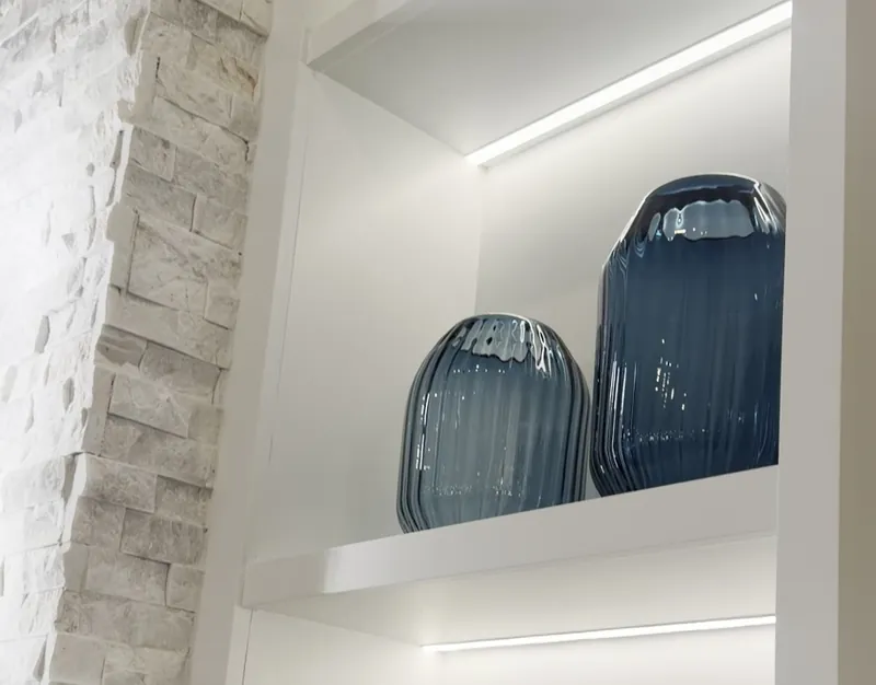 A white tower shelf with an LED strip underneath, beside the stacked stone