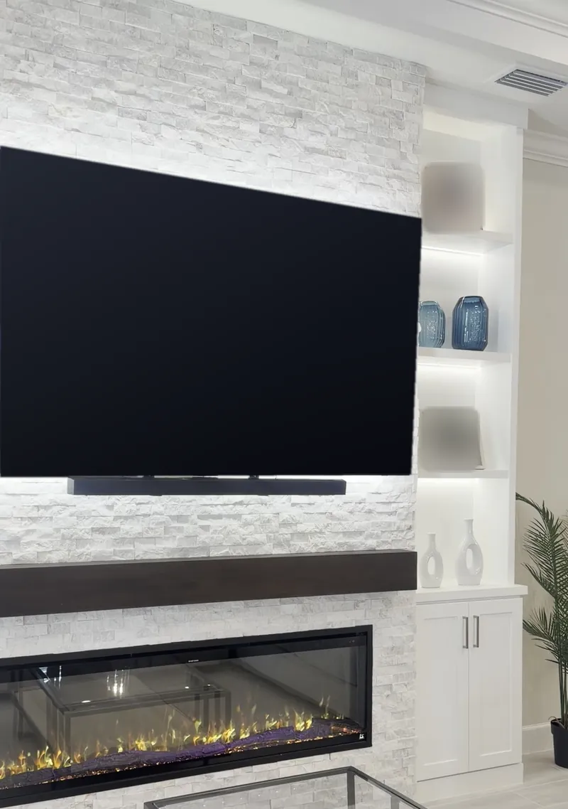 Angled view of the stone, the espresso-tone mantel, the fireplace and the right tower over its cabinets