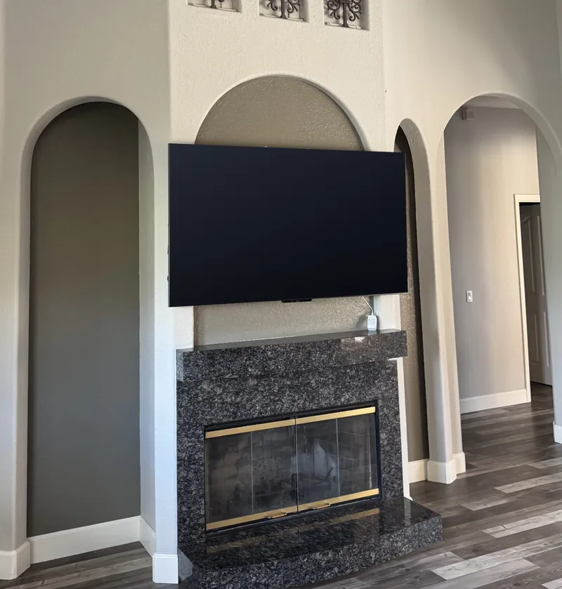 A living room wall with a dark stone fireplace and a TV, as it looked before