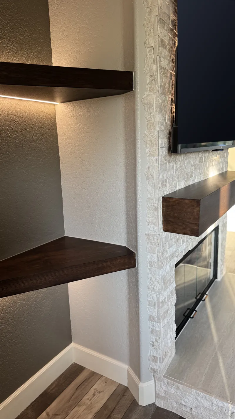 A dark floating shelf lit inside the arch, beside the stone