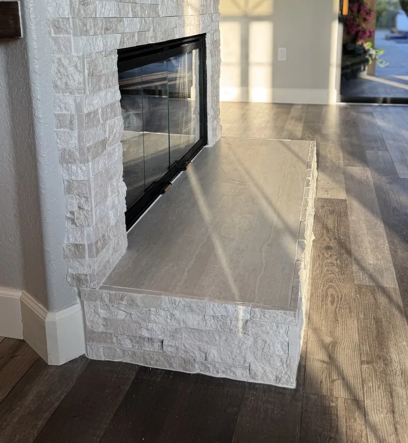 The raised stacked stone hearth in front of the fireplace