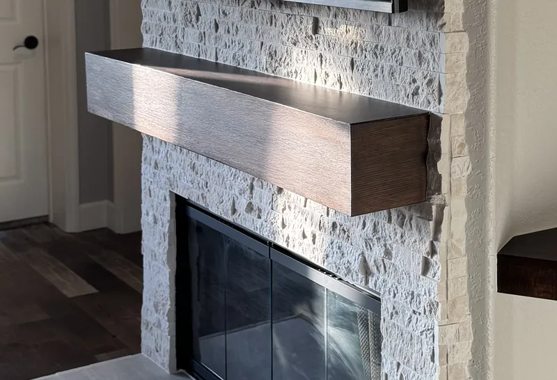 A dark wood-tone mantel over a stone fireplace