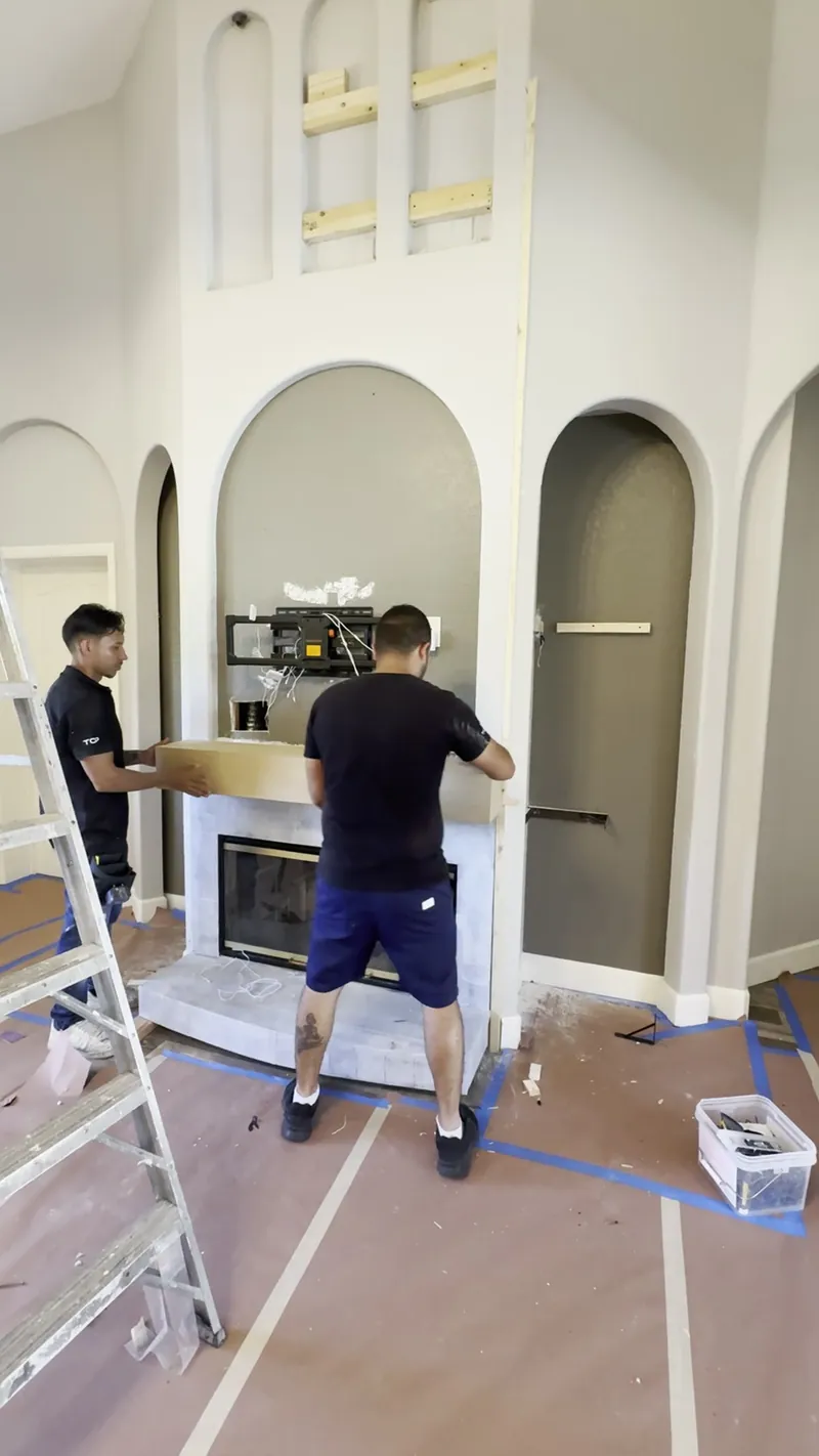 Two team members setting a mantel over the fireplace