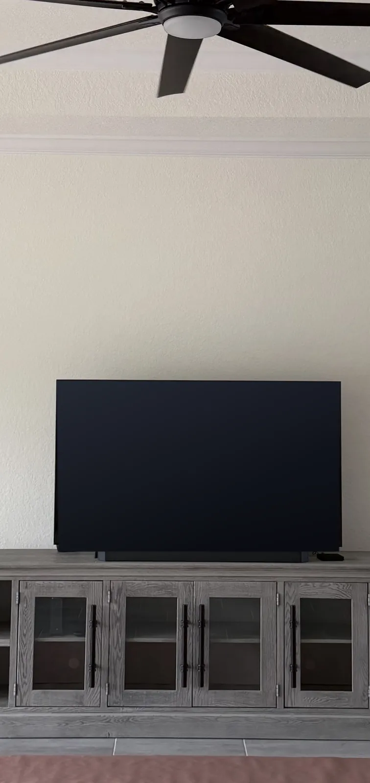 A plain living room wall with a TV on a console, before the project