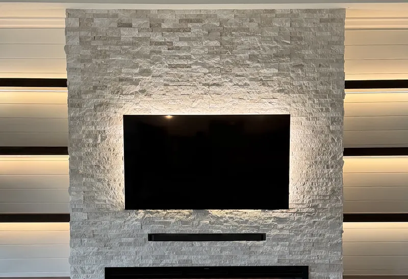 A backlit TV on stacked stone with a soundbar below
