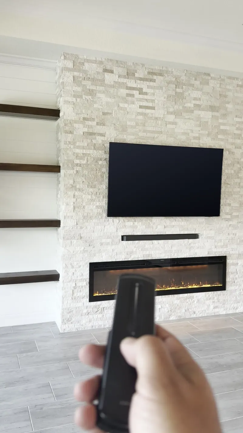 A hand pointing the remote at the lit stone wall