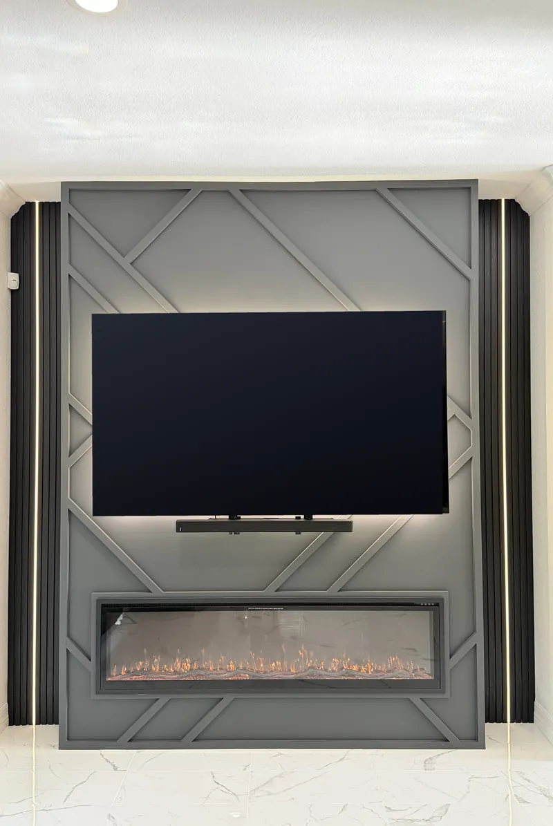 The Graphite Diamond Wall straight on: raised diagonal trim on a graphite panel, the TV, the linear fireplace and black slats with lines of light
