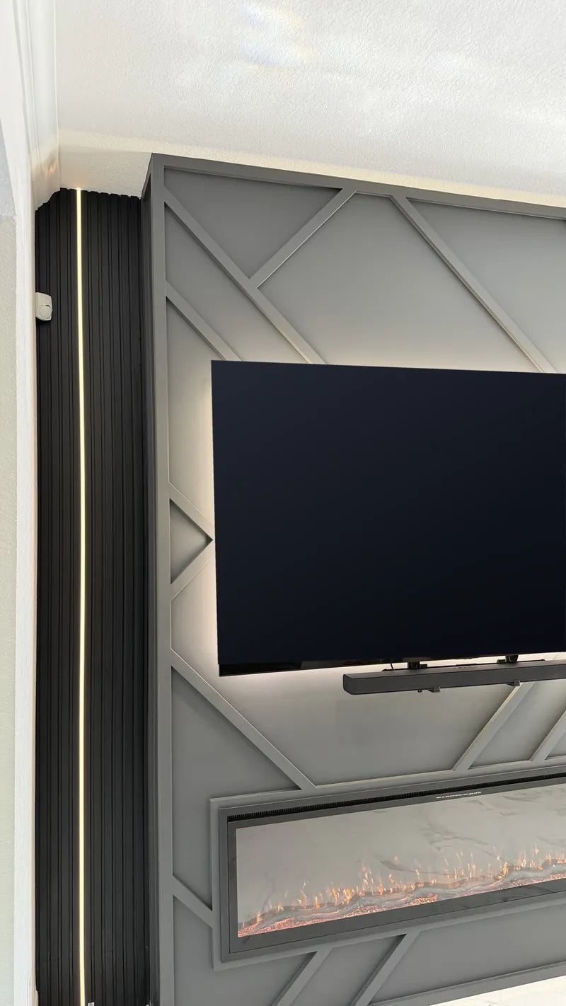 Angled view of the diagonal trim, the TV and the black slats with a line of light