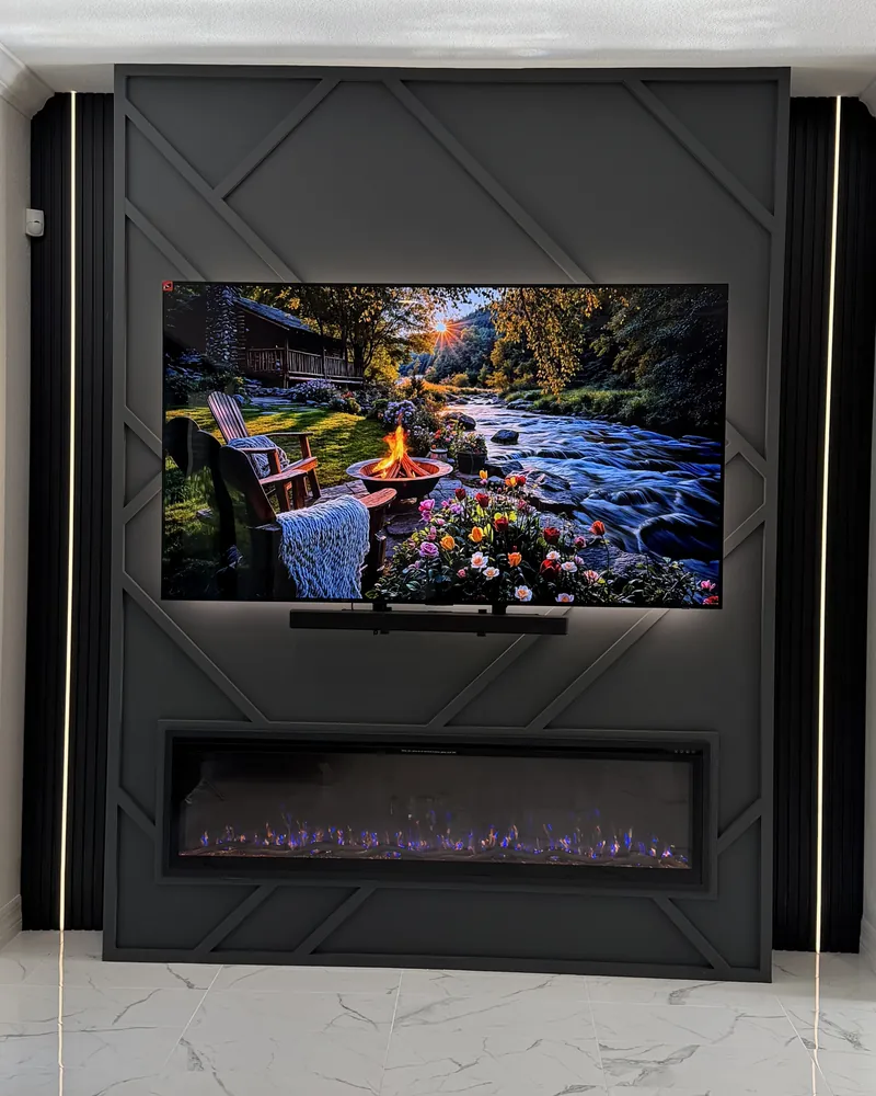 Graphite wall with a diamond pattern of trim around a backlit TV and a linear fireplace
