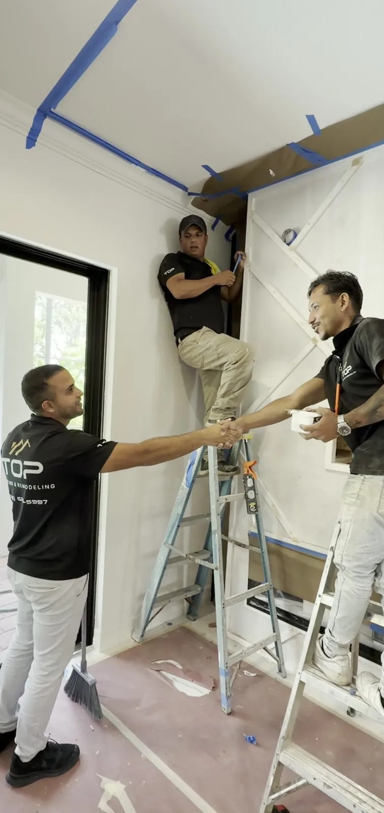 Two team members on ladders building a feature wall
