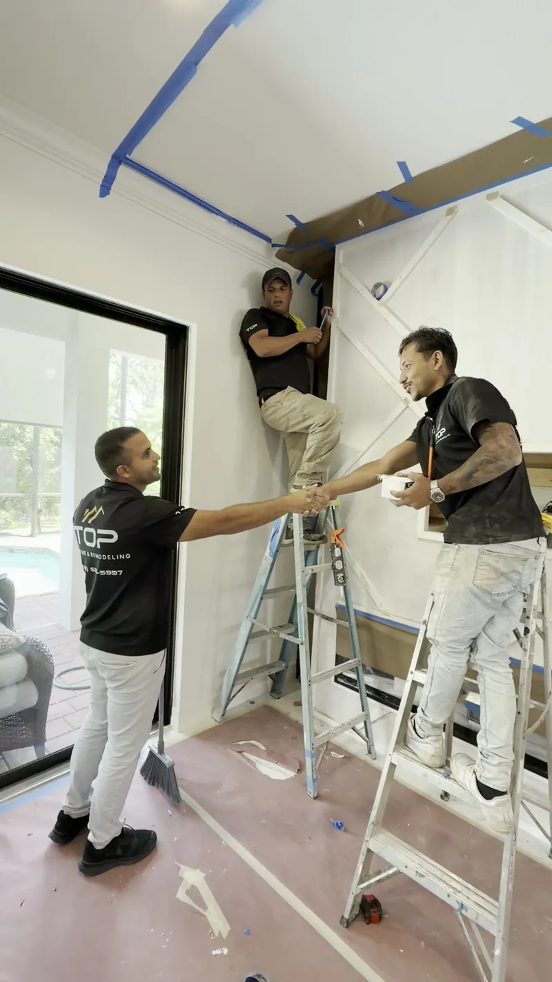 Two team members on ladders building a feature wall