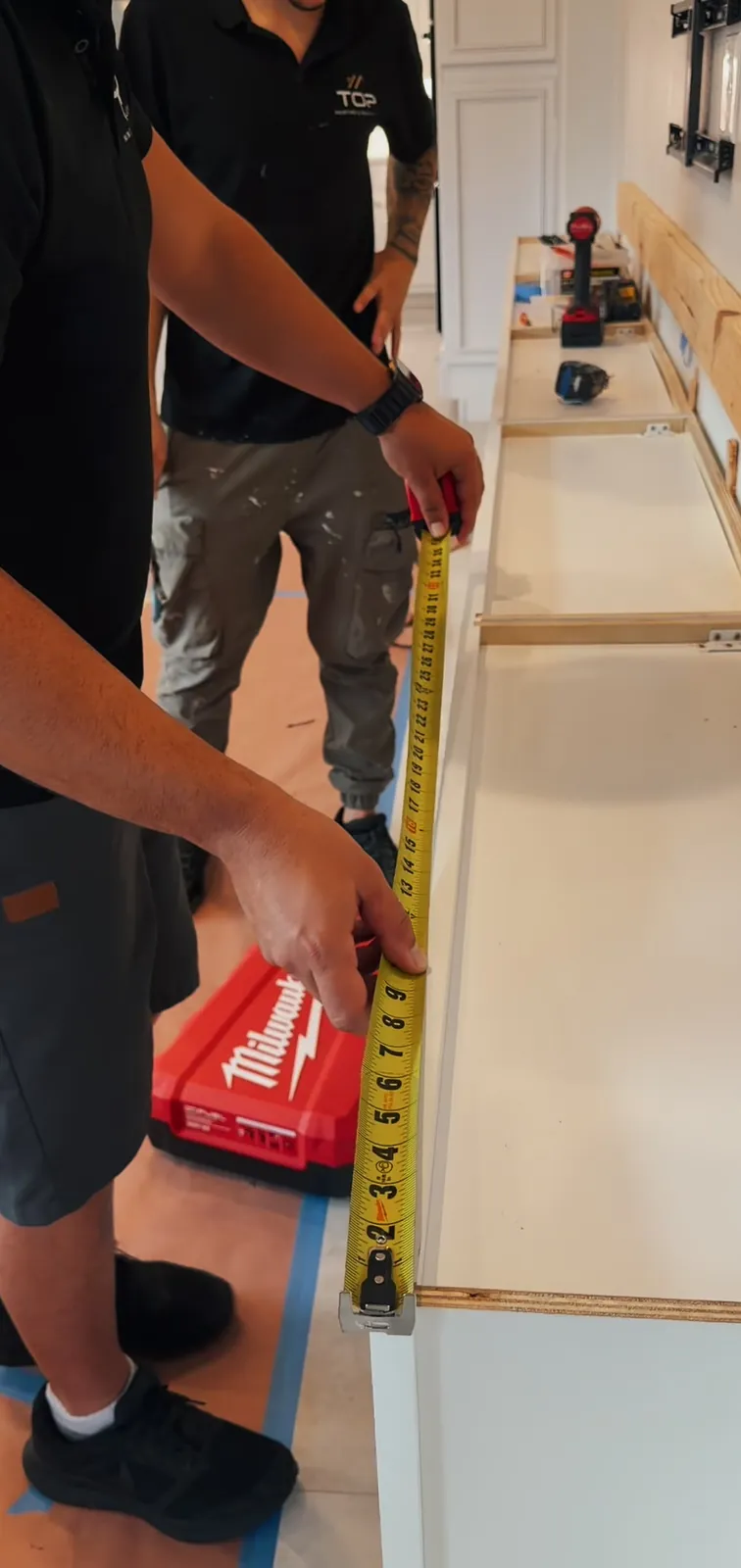 A tape measure running along a cabinet base during measuring