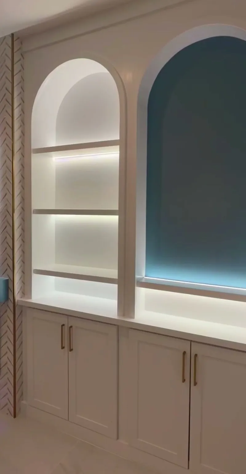 Arched niches lit from within over white cabinets, one niche in a deep blue-green