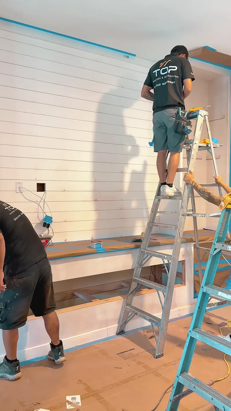 A team member on a ladder installing shiplap boards