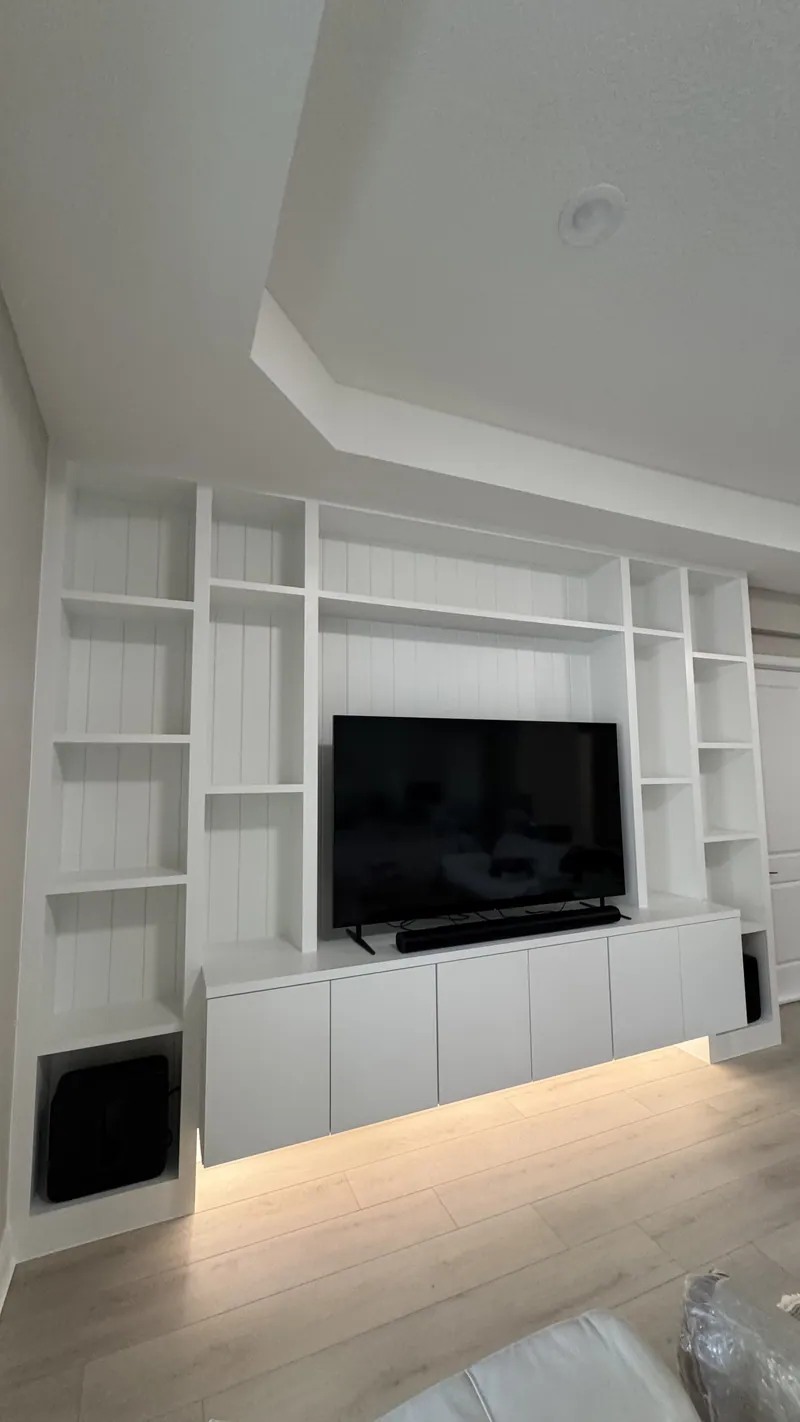 White built-in media wall with open shelves and an under-lit floating console